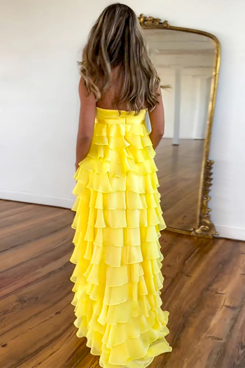 Front view of yellow strapless A-line gown with tiered skirt.