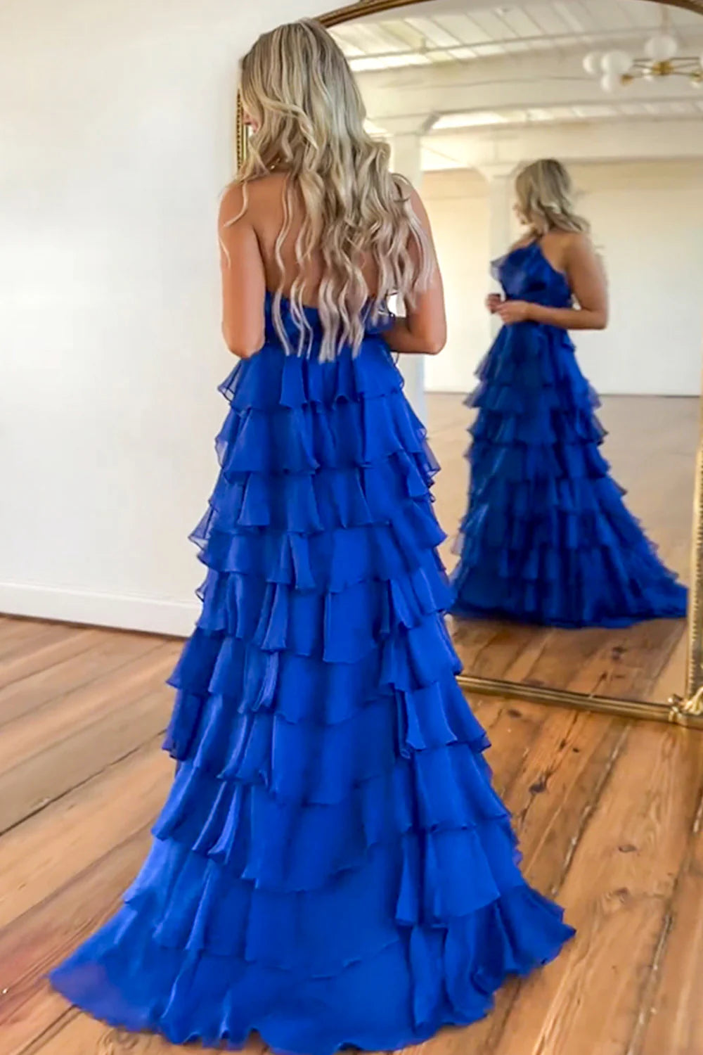 Back view of royal blue A-line prom dress showing open back and floor length skirt.