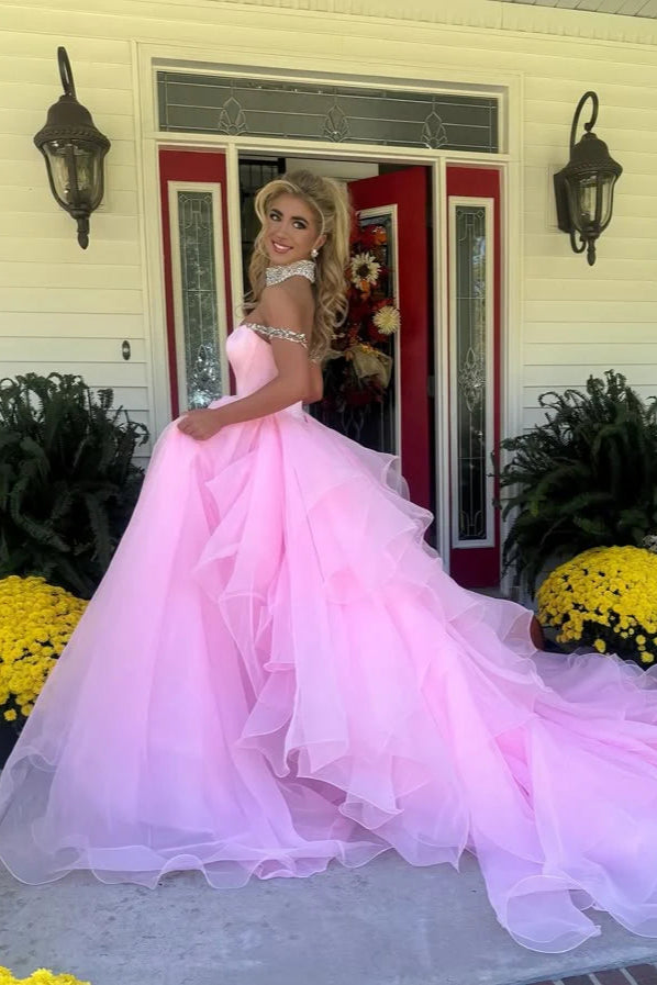 Model wearing an elegant A-line off-shoulder pink prom dress with beading and rhinestones.