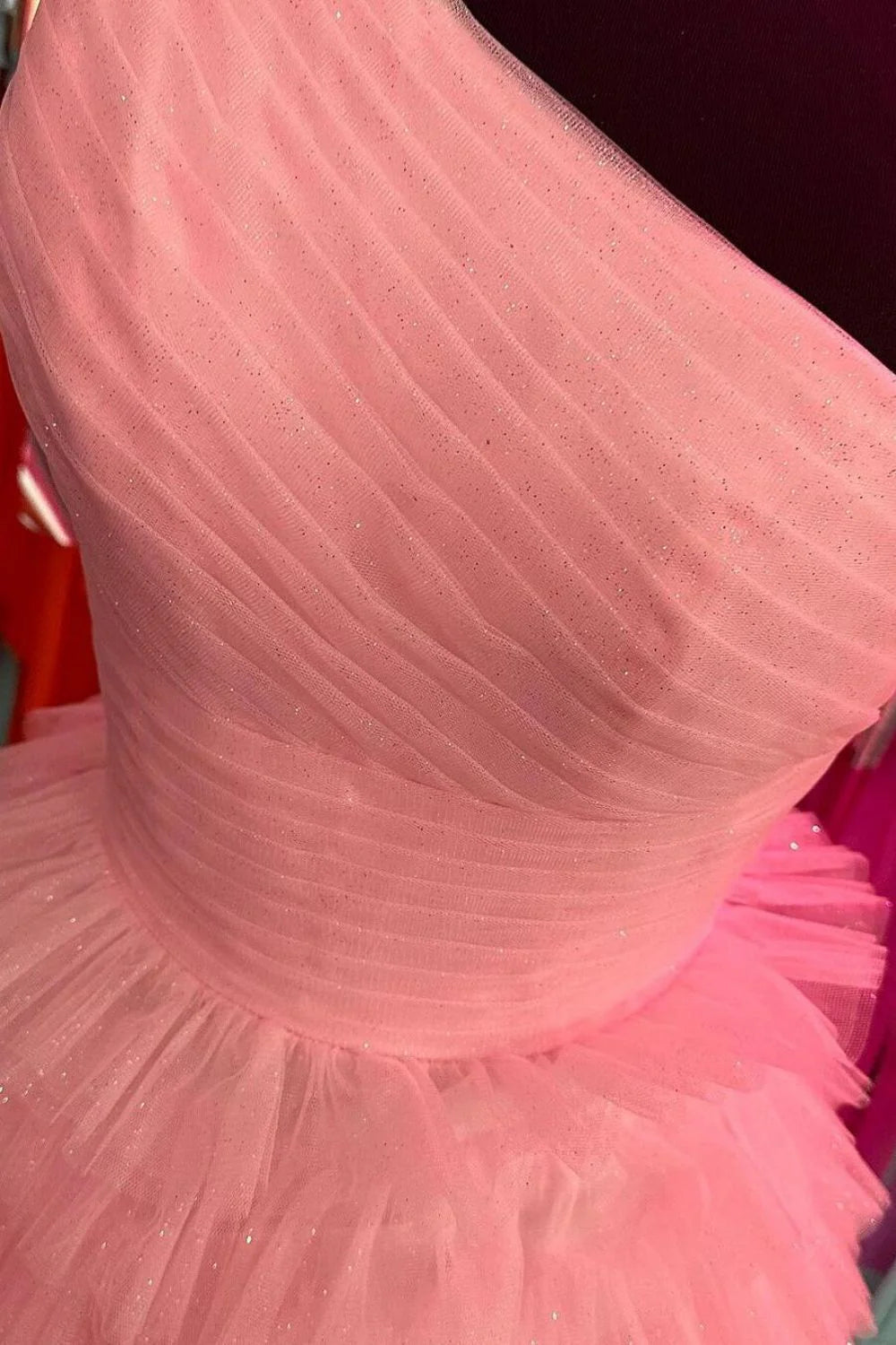 Model posing in a graceful pink A-line one-shoulder pleated tiered ruffle prom dress, side profile.