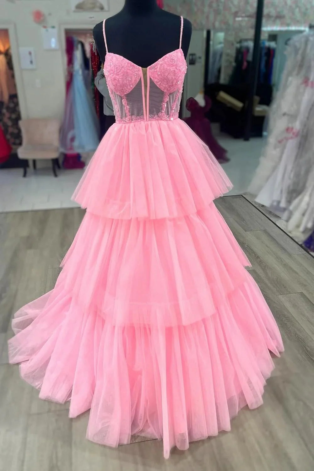 Elegant pink A-line prom dress with spaghetti straps, applique corset, and tiered tulle skirt.