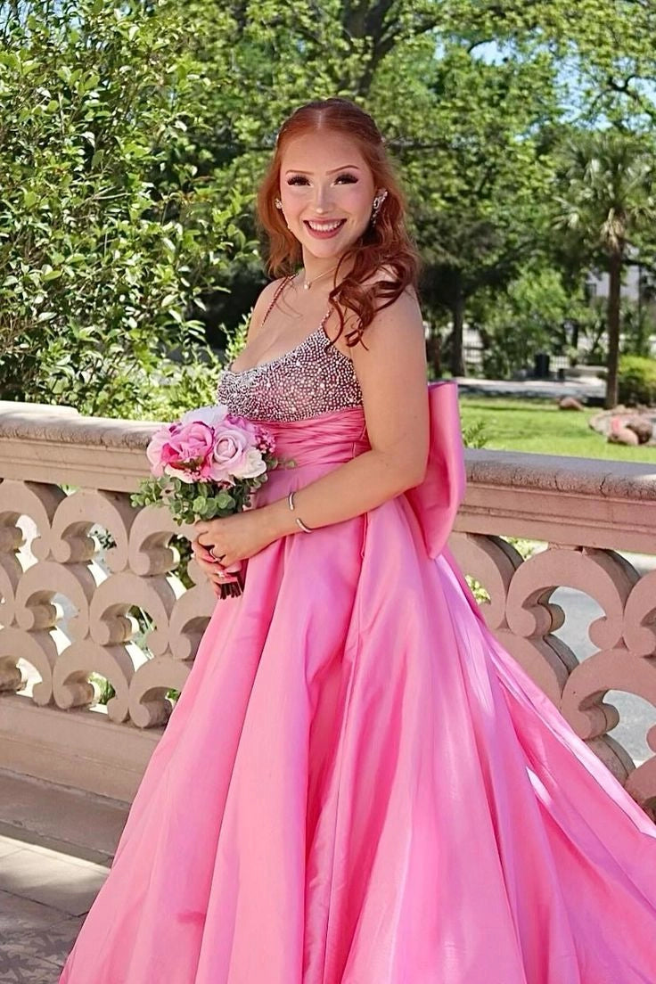 Elegant pink A-line prom dress with spaghetti straps, beaded bodice, and large back bowknot.