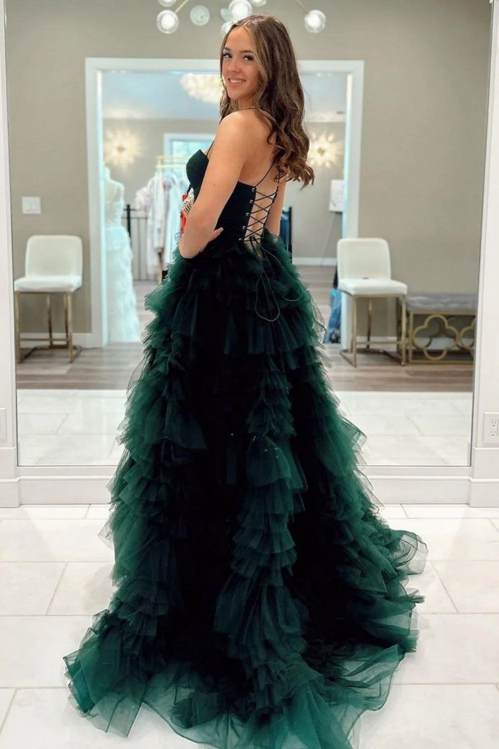 Model wearing a dark green A-line prom dress with spaghetti straps, bodycon bodice, and a dramatic high slit.