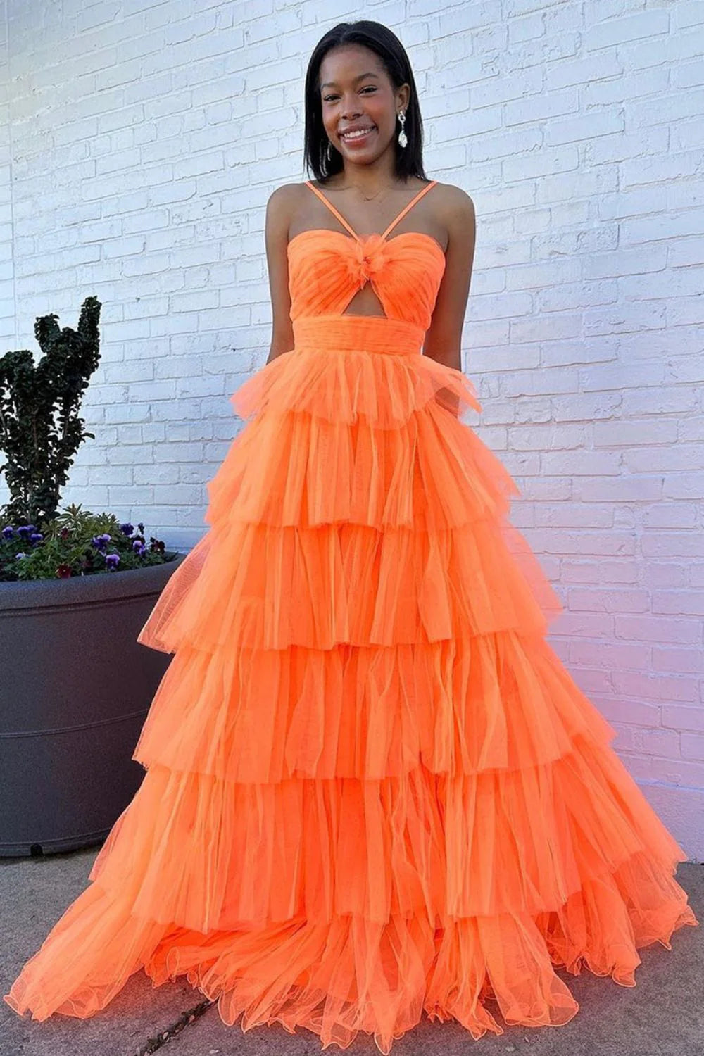 Orange A-line prom dress with spaghetti straps and tiered ruffles, back view.