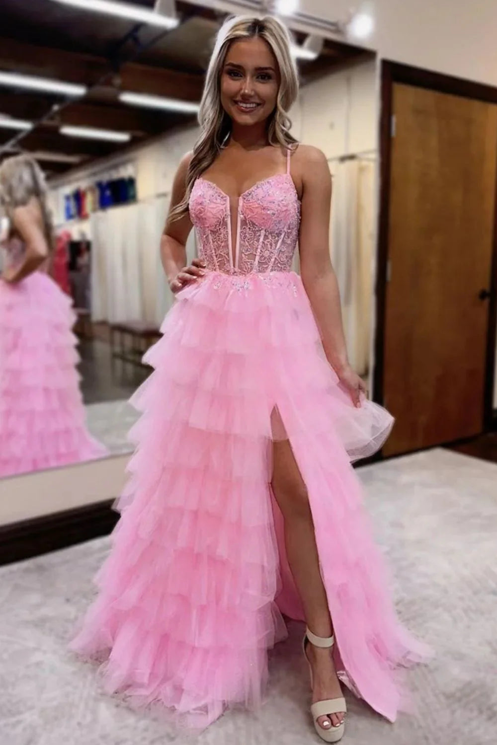 Model in pink A-line tiered tulle prom dress, side view.