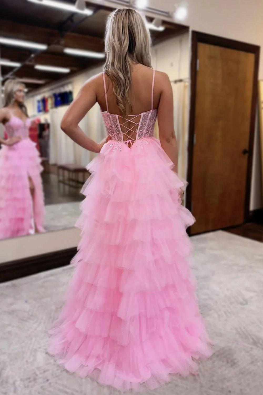 Model in pink A-line tiered tulle prom dress, front view.