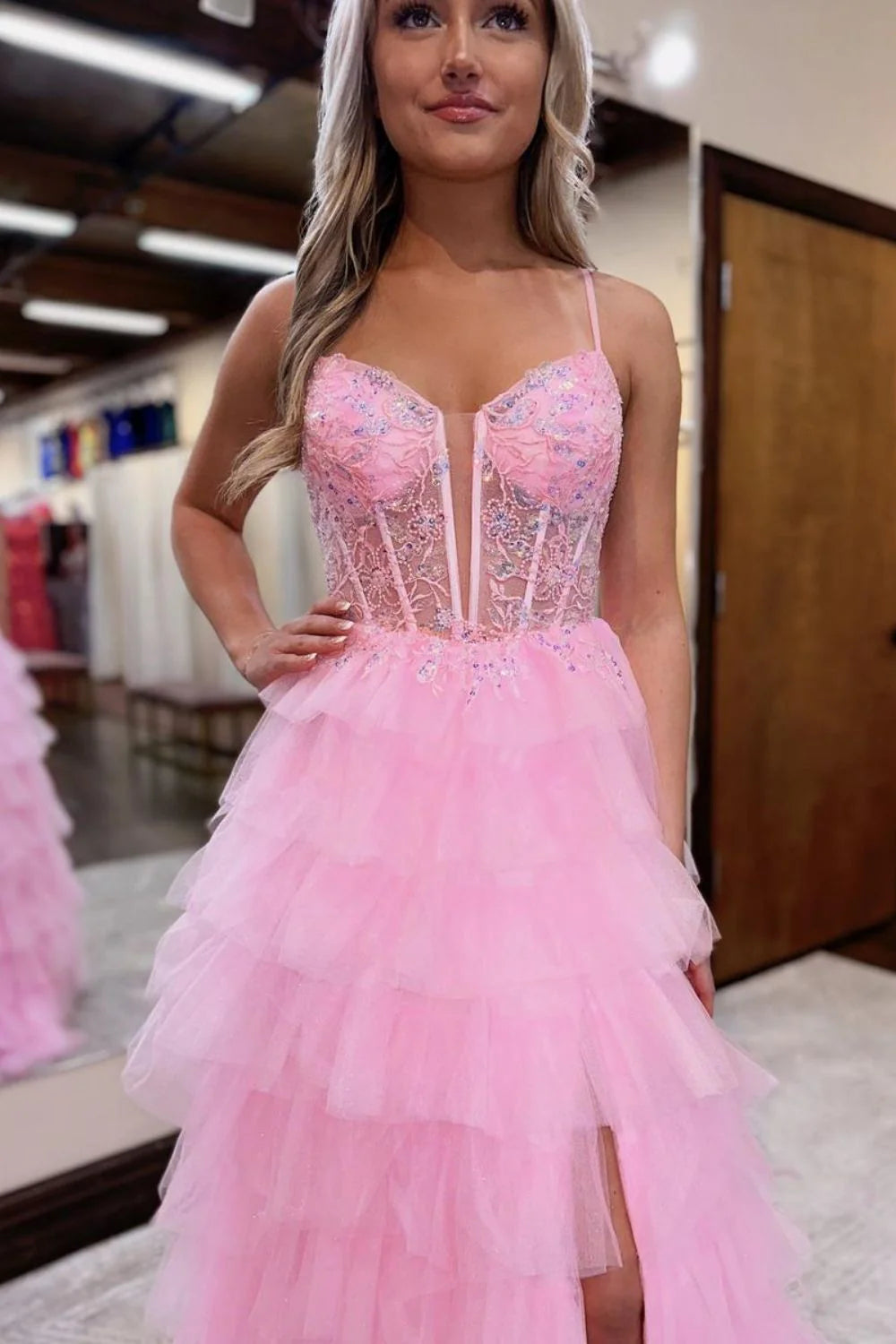 Model in pink A-line tiered tulle prom dress, back view with lace-up detail.