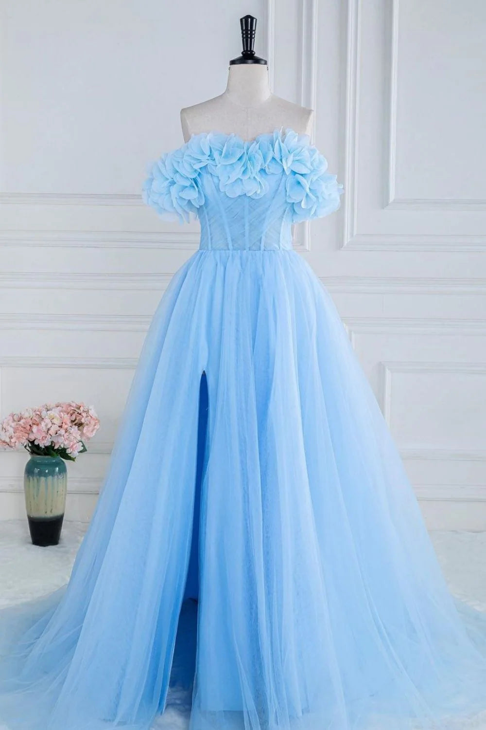 Model wearing an elegant blue A-line strapless prom dress with 3D flowers and a corset bodice.