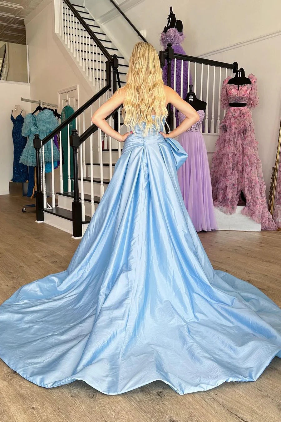 Full-length view of a light blue satin strapless prom dress with a side bow.