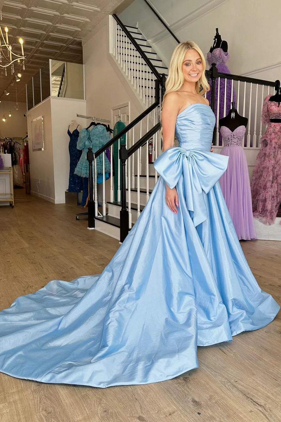 Back view of a light blue A-line prom dress showing the court train and zipper closure.