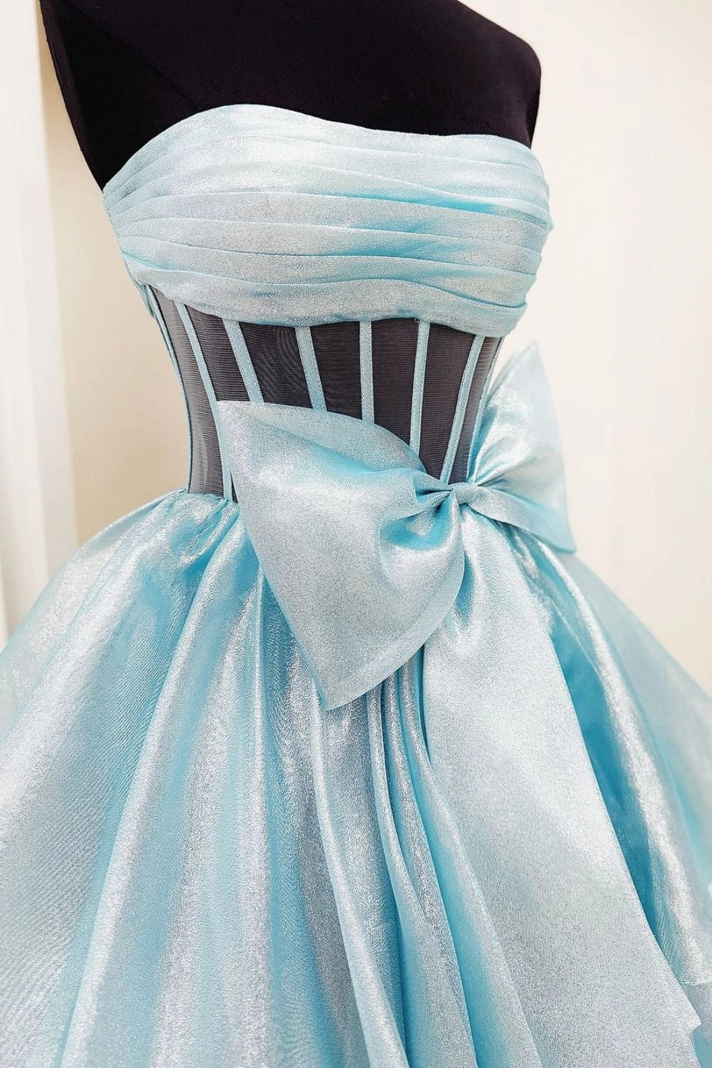 Model wearing a fuchsia A-line strapless prom dress with a bowknot and slit, back view.