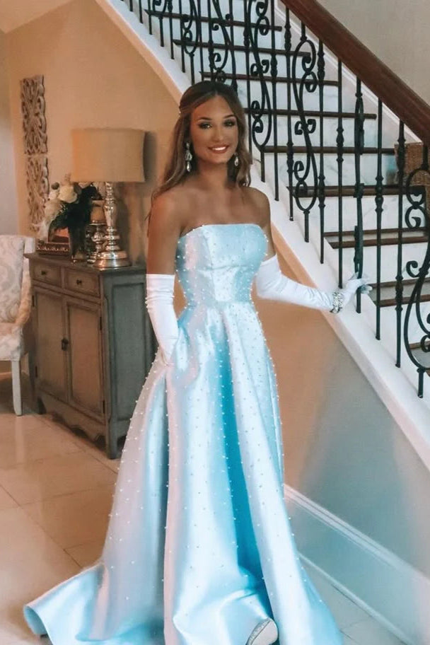 Woman wearing an elegant A-line strapless light blue prom dress with pearl embellishments.