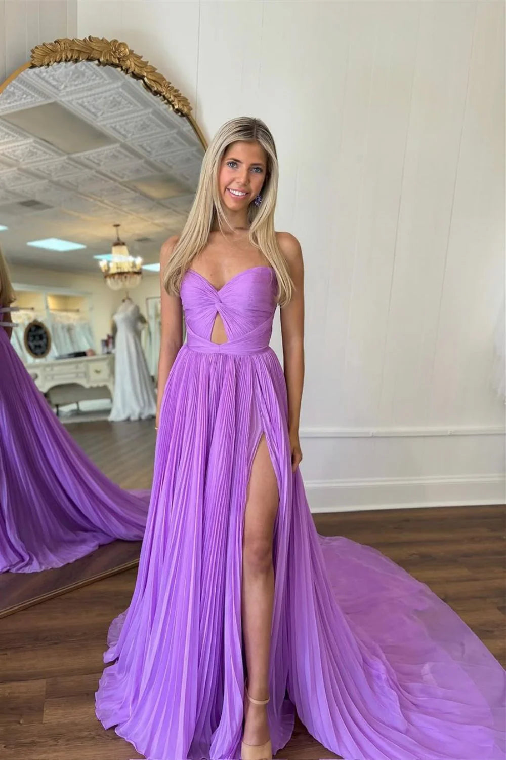 Model wearing a long A-line strapless purple prom dress, showcasing pleated tulle fabric.
