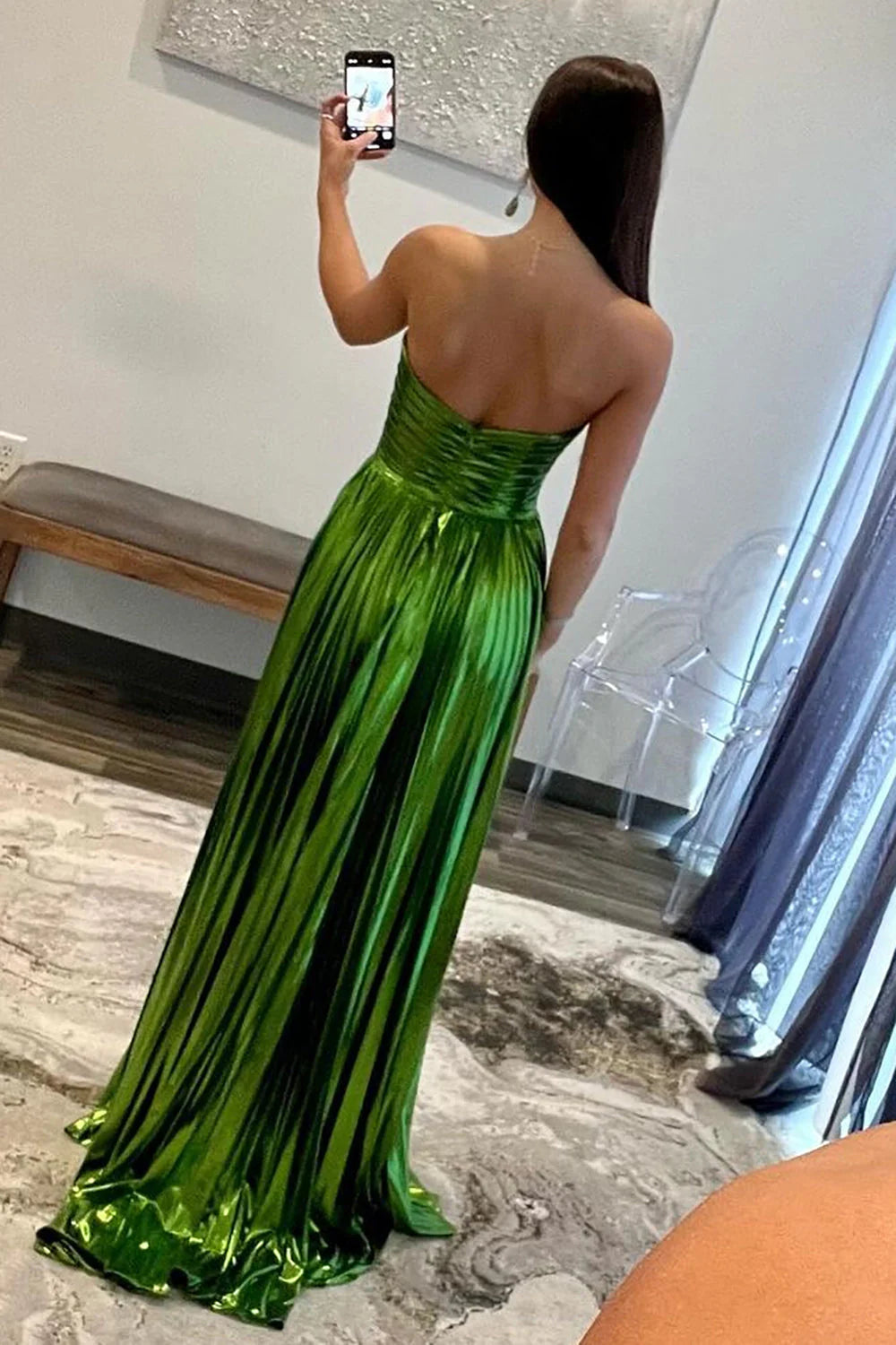 Back view of metallic green strapless A-line gown with open back design.