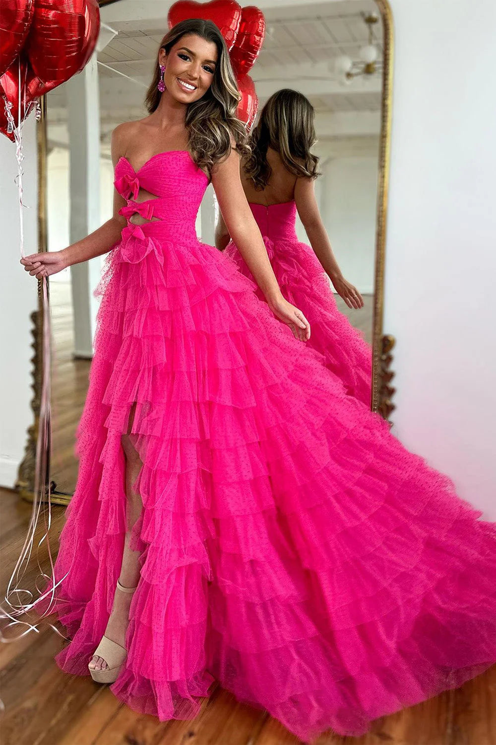 Model wearing a fuchsia A-line prom dress with sweetheart neckline, bowknot, tiered tulle skirt, and high slit.