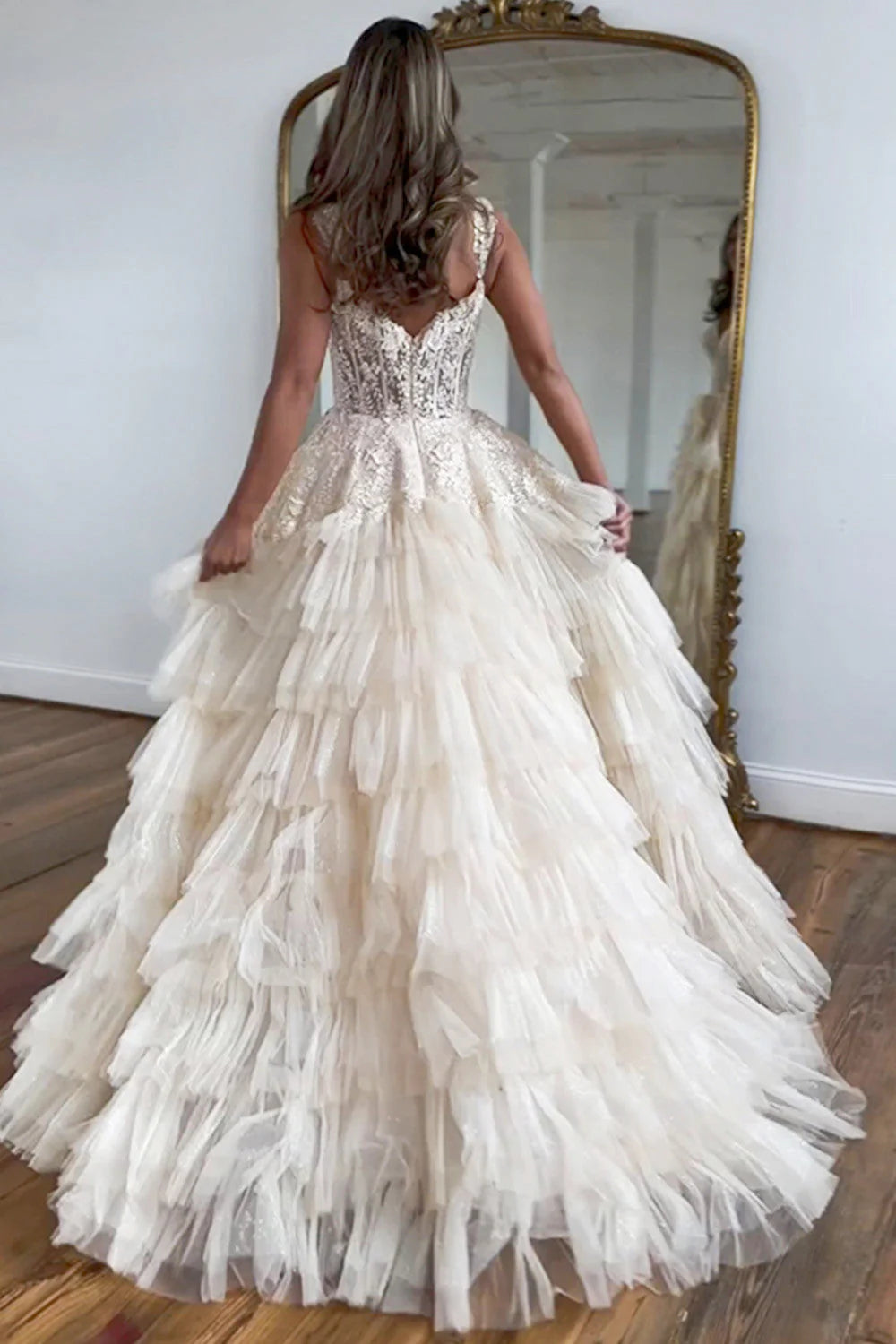 Side view of a champagne A-line prom dress showing tiered tulle skirt and back zipper.