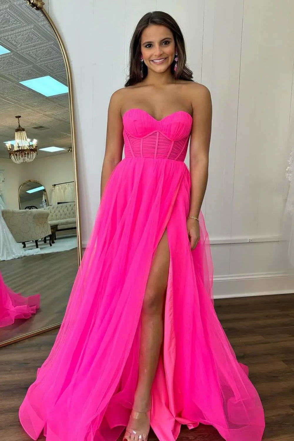 Model wearing a hot pink A-line sweetheart long prom dress with a high side slit.