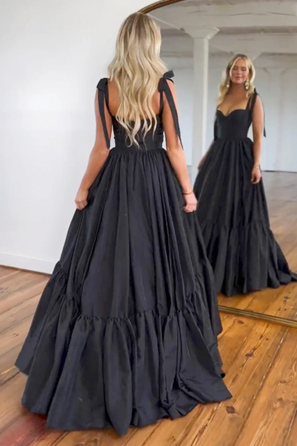 Close-up of the smooth black satin fabric and delicate tie straps on the A-line prom dress.