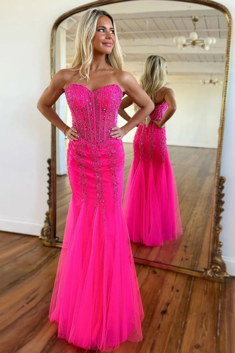Model wearing a hot pink mermaid prom dress with a sweetheart neckline and beaded tulle skirt.