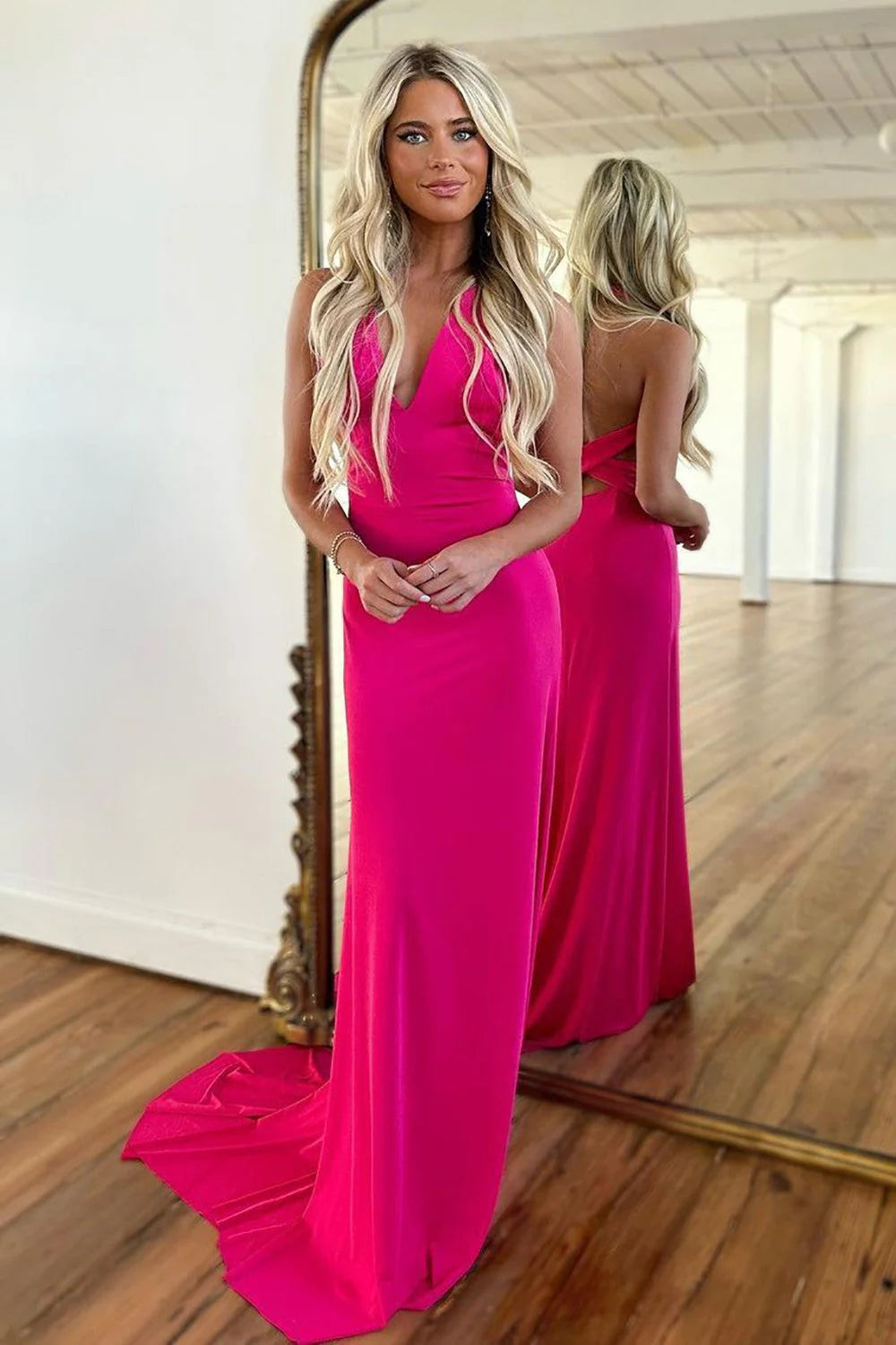 Model wearing a hot pink satin V-neck corset cross-back long prom dress, showing the back detail.