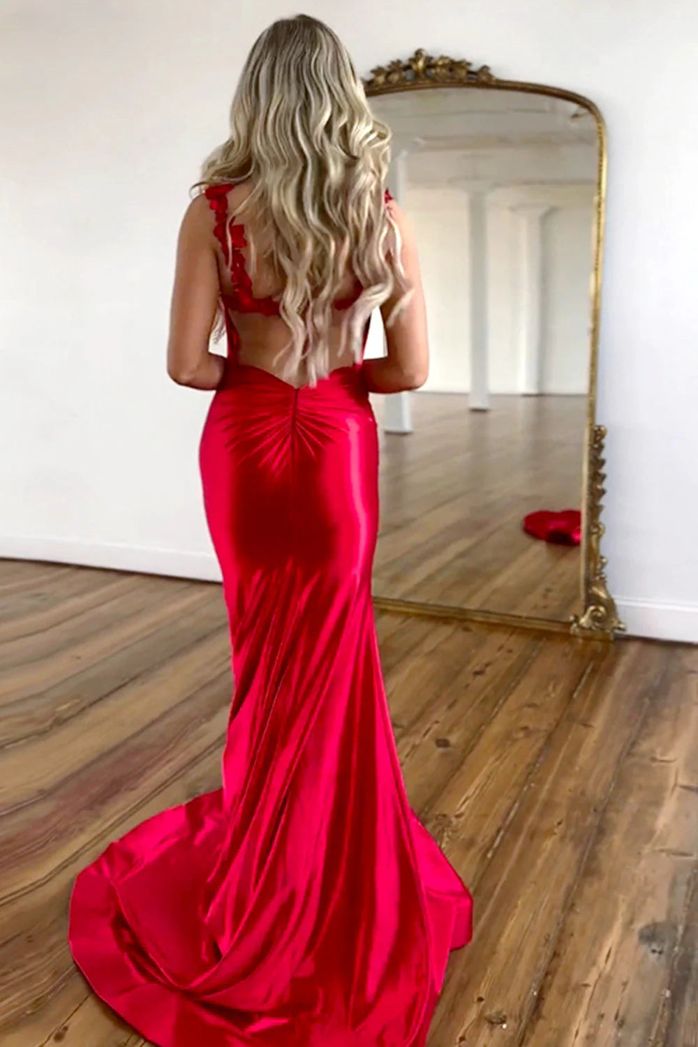 Side view of red satin mermaid gown with open back and train.