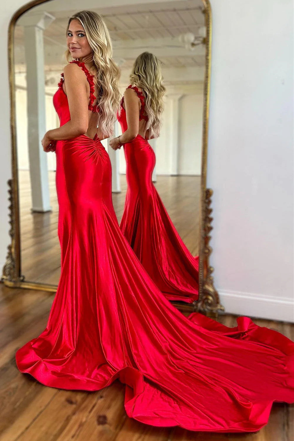 Back view of red mermaid prom dress, highlighting open back and train.