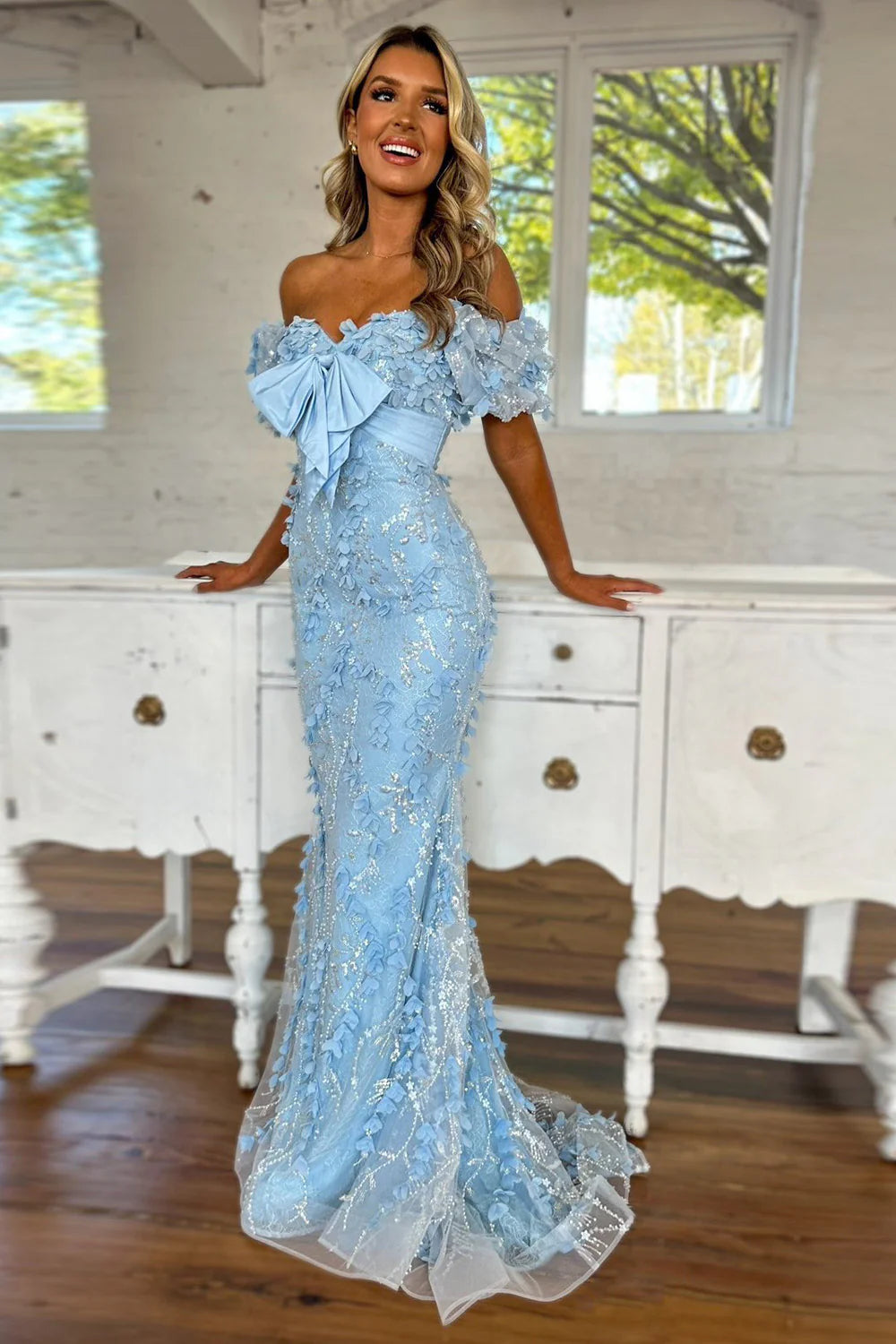 Woman wearing an elegant light blue mermaid off-shoulder glitter prom dress.