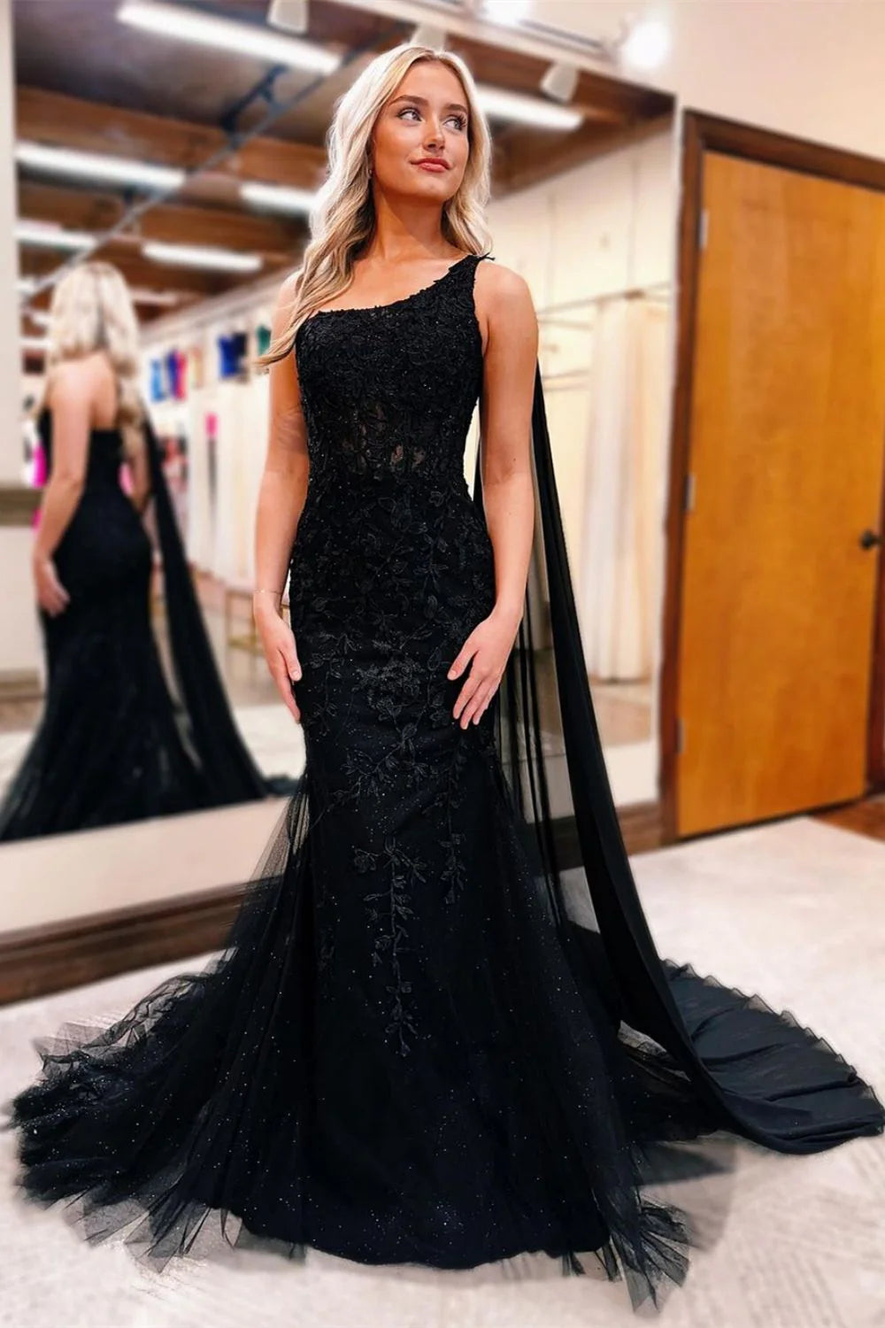 Black mermaid prom dress with one shoulder, beaded lace bodice, and flowing train.