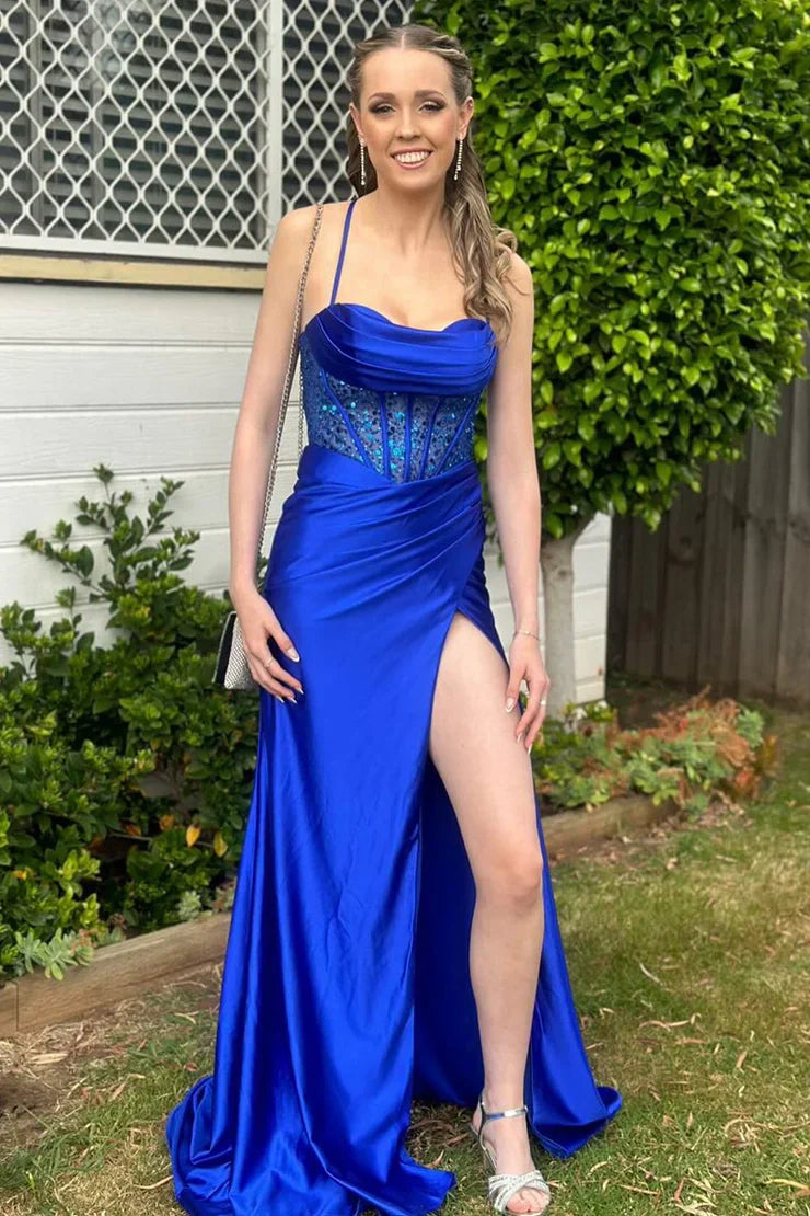Model posing in a red mermaid prom dress, highlighting the split and spaghetti straps.