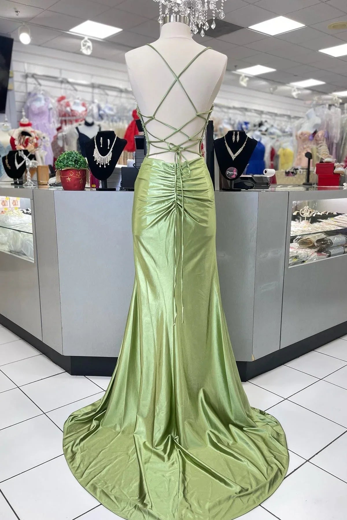 Full-length view of a woman in a green mermaid gown, highlighting the sweep train and elegant silhouette.