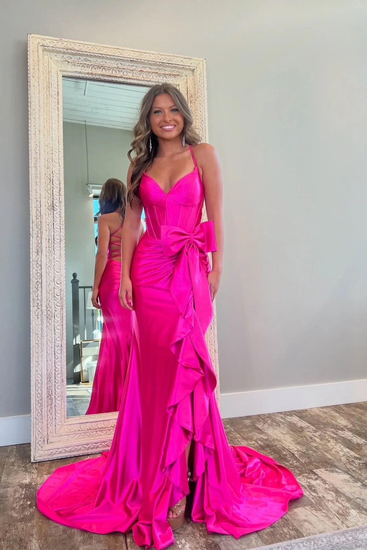 Model posing in a hot pink mermaid prom dress, highlighting the spaghetti straps.
