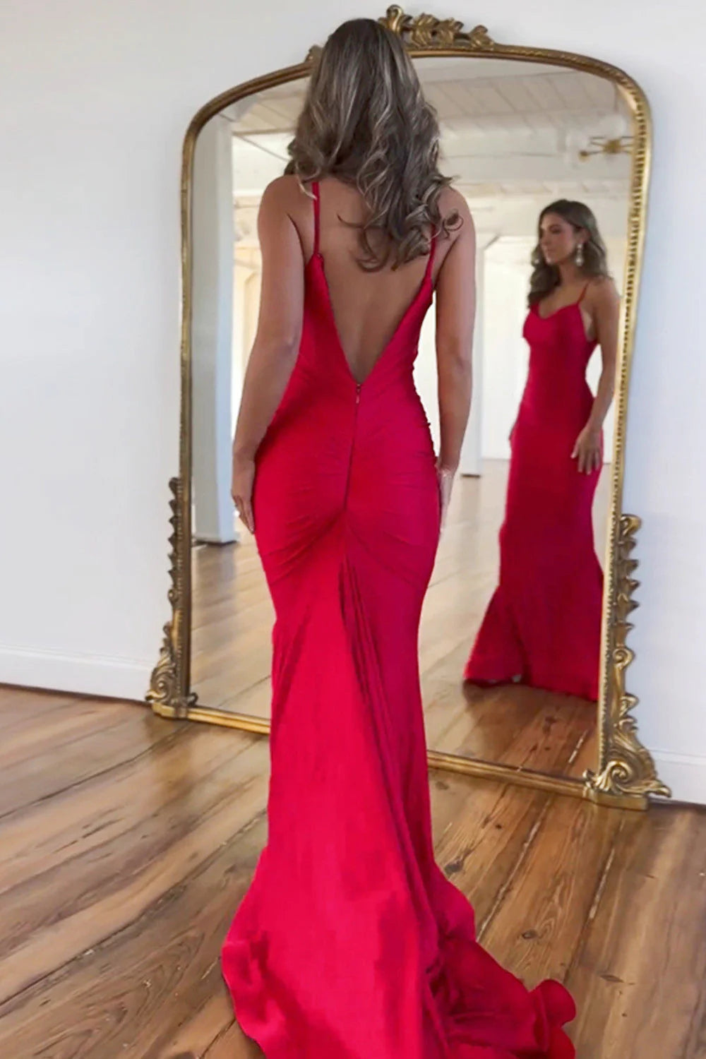 Red satin mermaid prom dress with a long train, side view.