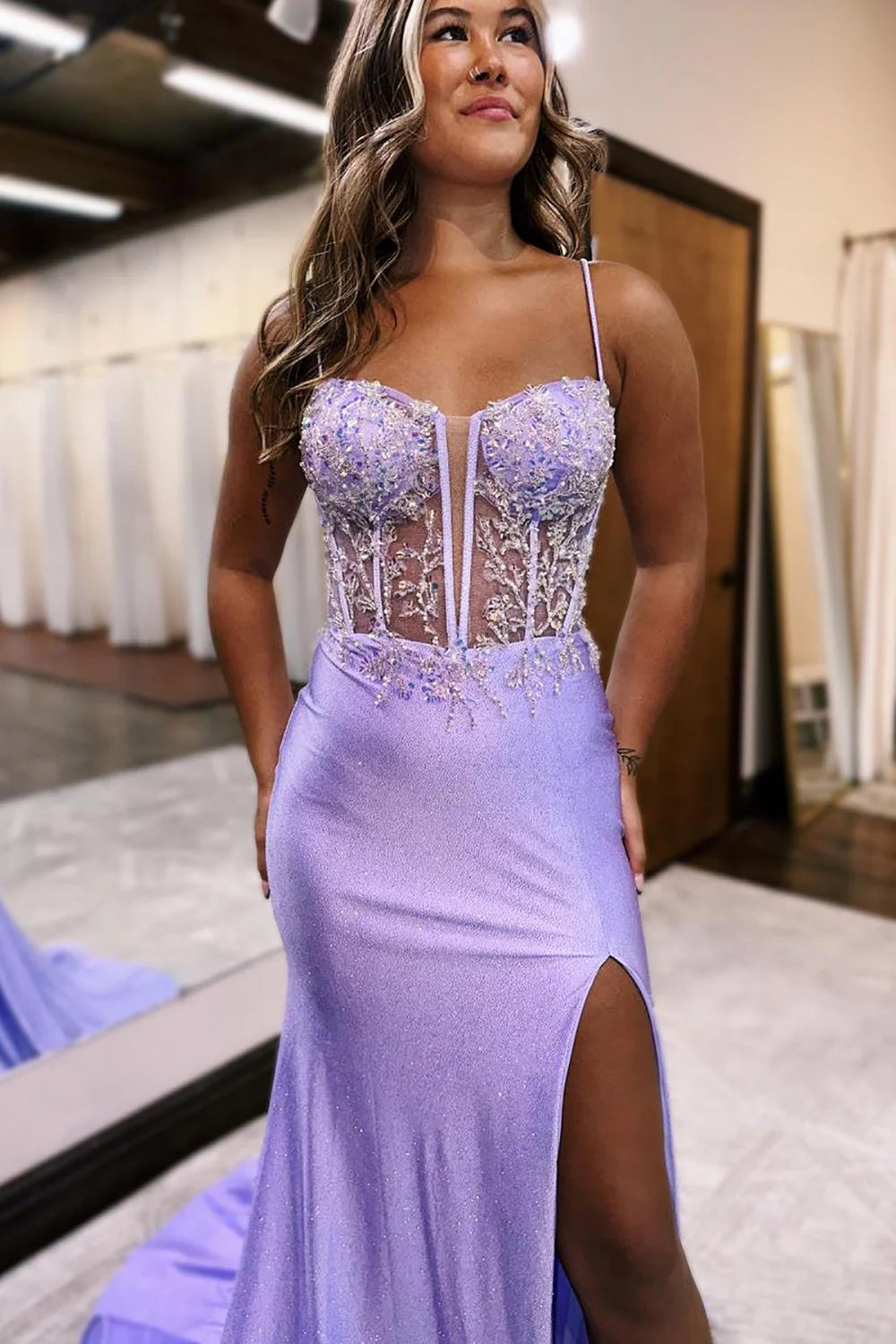 Front view of a woman in a lilac mermaid prom dress with spaghetti straps and sparkling bodice.