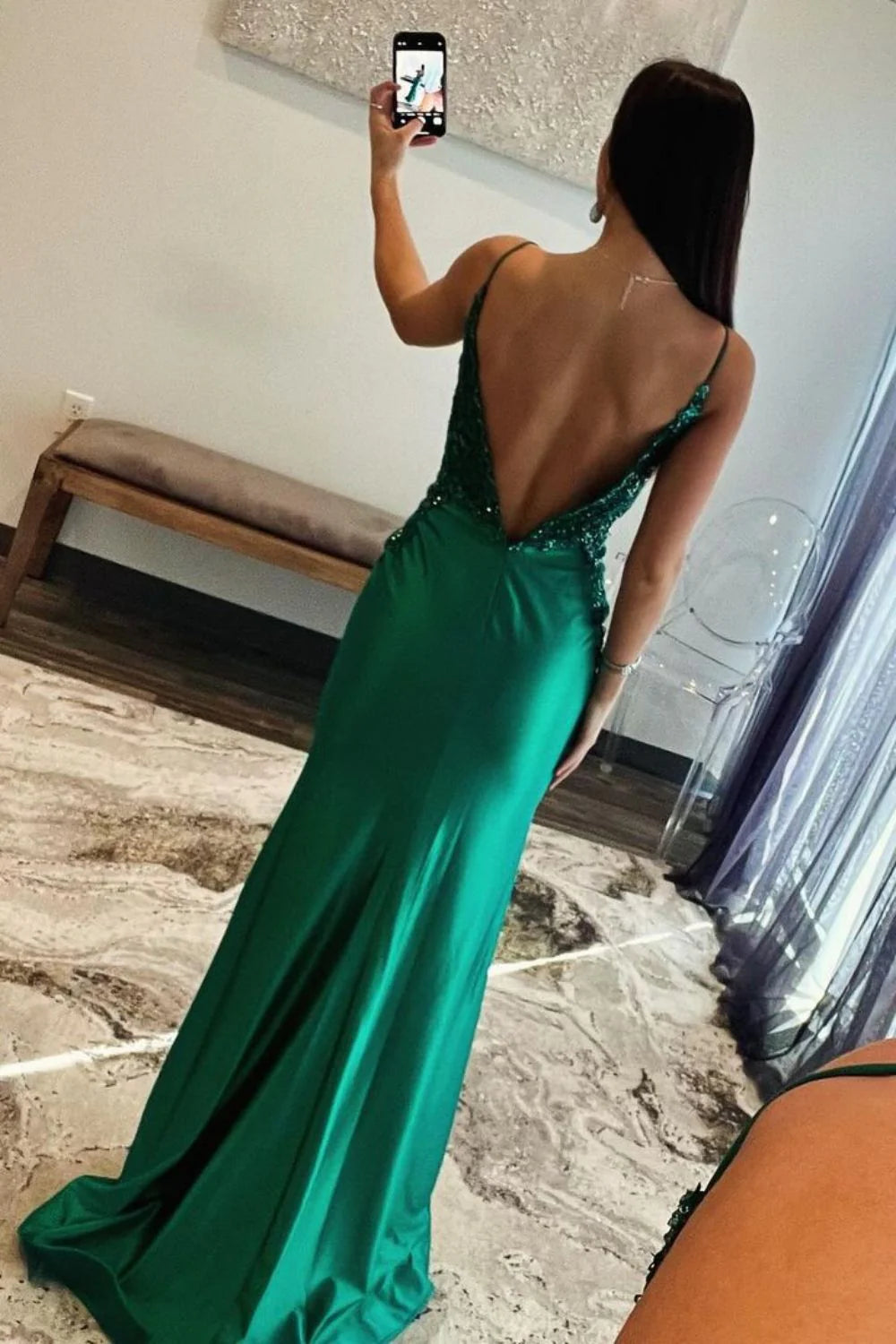 Back view of a dark green satin mermaid gown featuring an open back design.