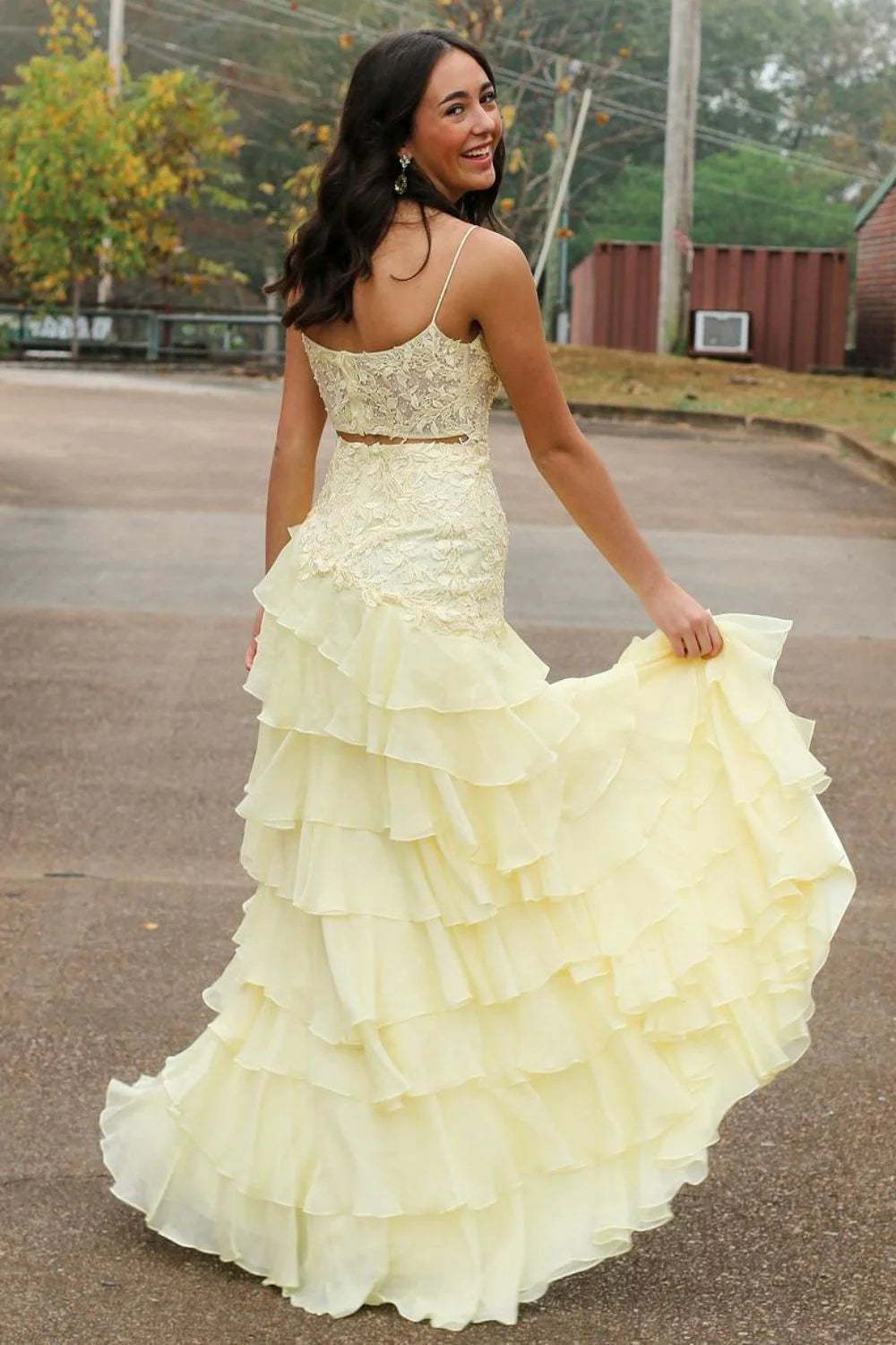 Back view of yellow mermaid prom dress featuring open back and ruffled skirt.