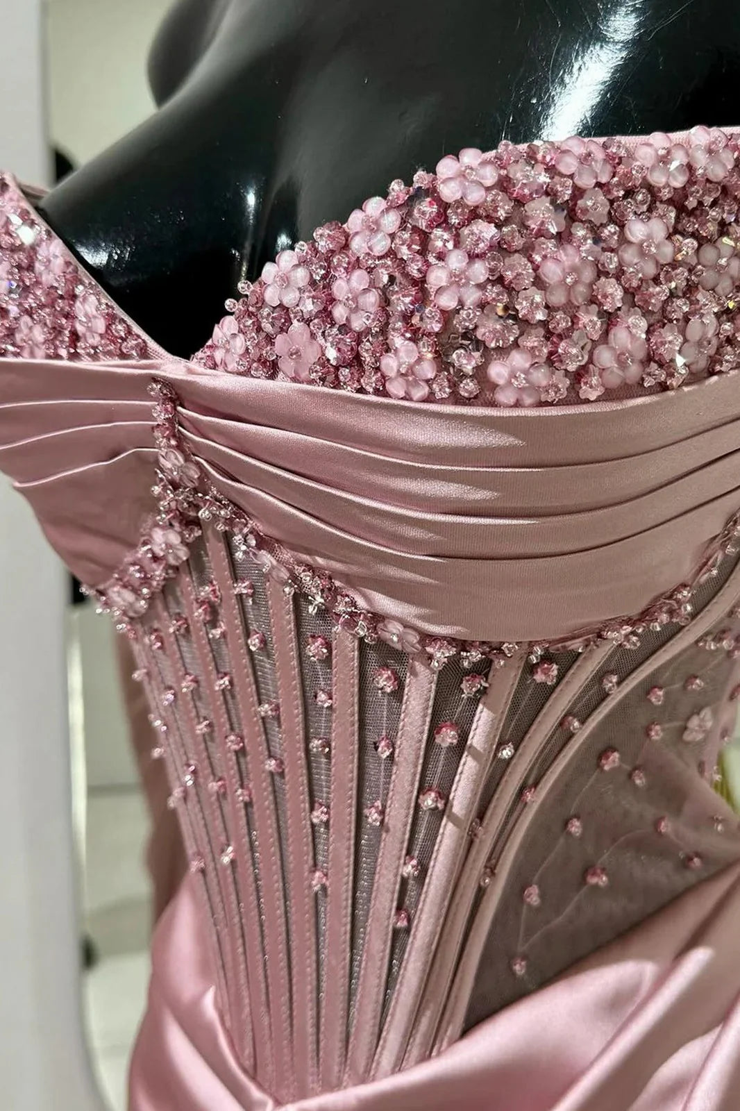 Back view of a woman in a pink mermaid prom dress with lace-up detail.