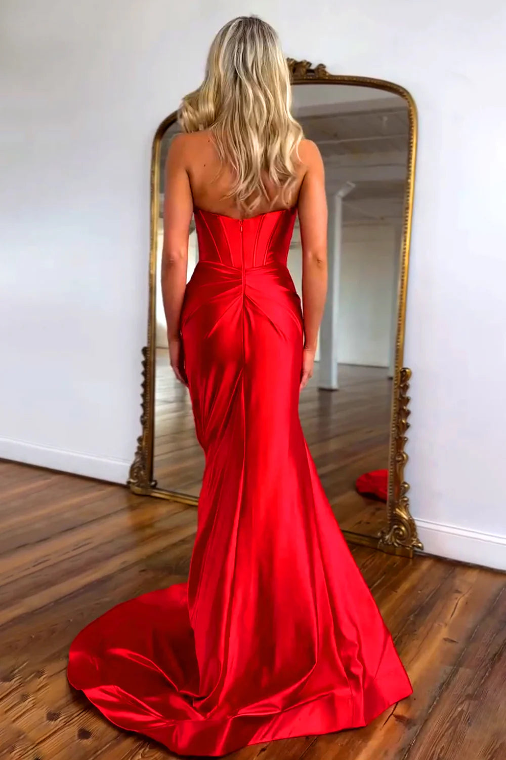 Full-length view of a red satin mermaid prom dress, featuring a strapless design, bowknot detail, and a front slit.