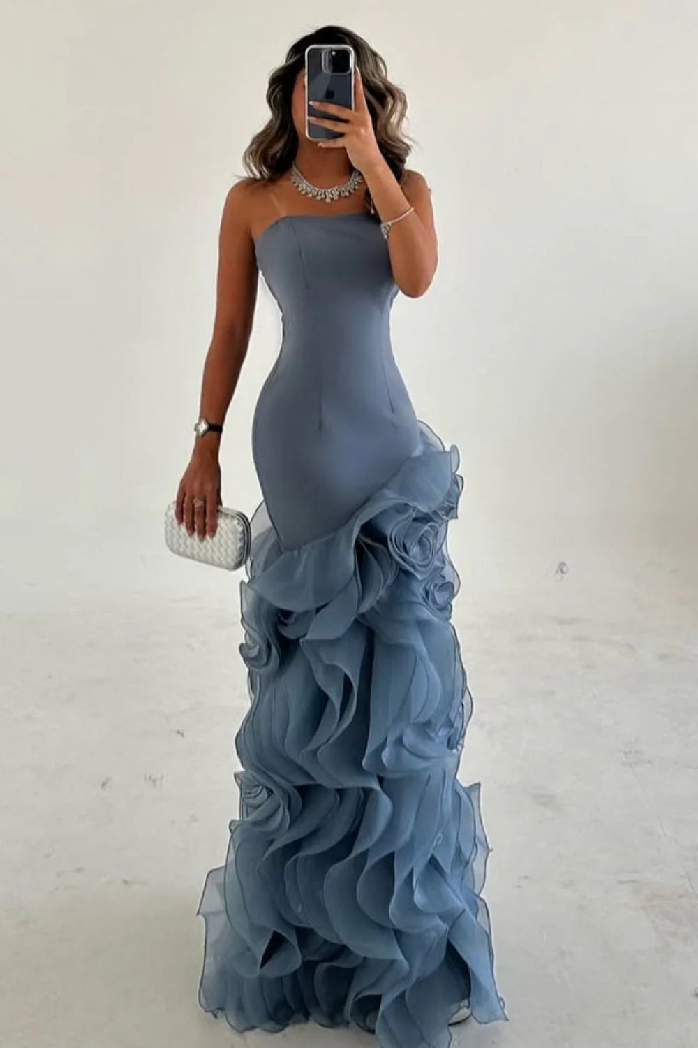Model in a dusty blue mermaid strapless prom dress with ruffled tulle, side view.