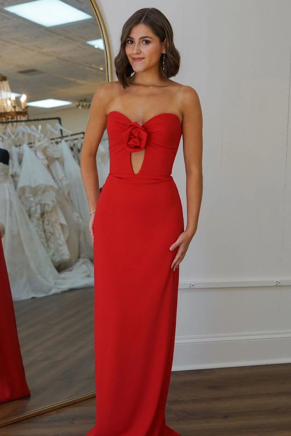 Model wearing a red satin mermaid prom dress with a sweetheart neckline and rose flower detail.