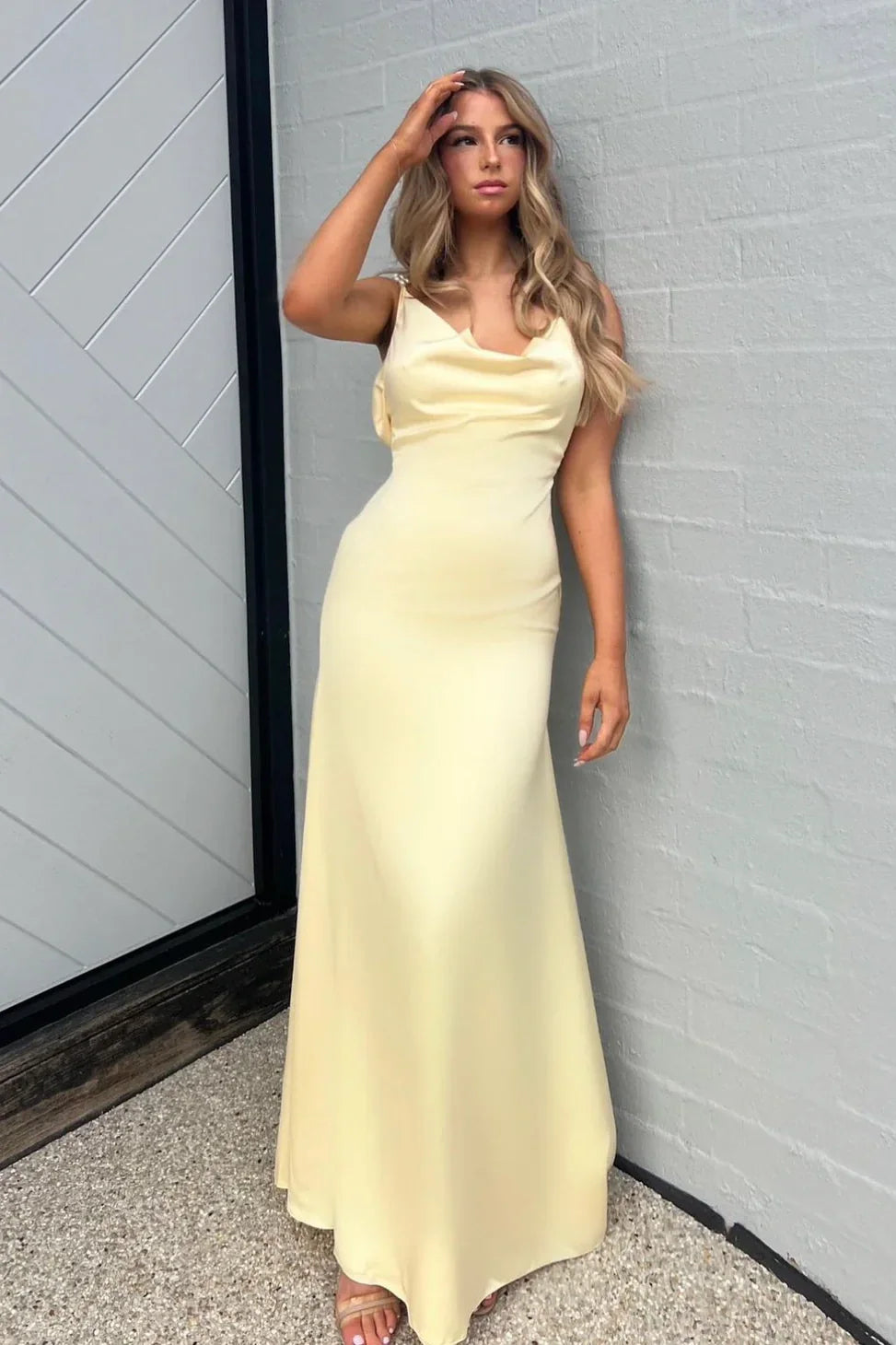Woman in an elegant pearl yellow sheath prom dress with spaghetti straps.