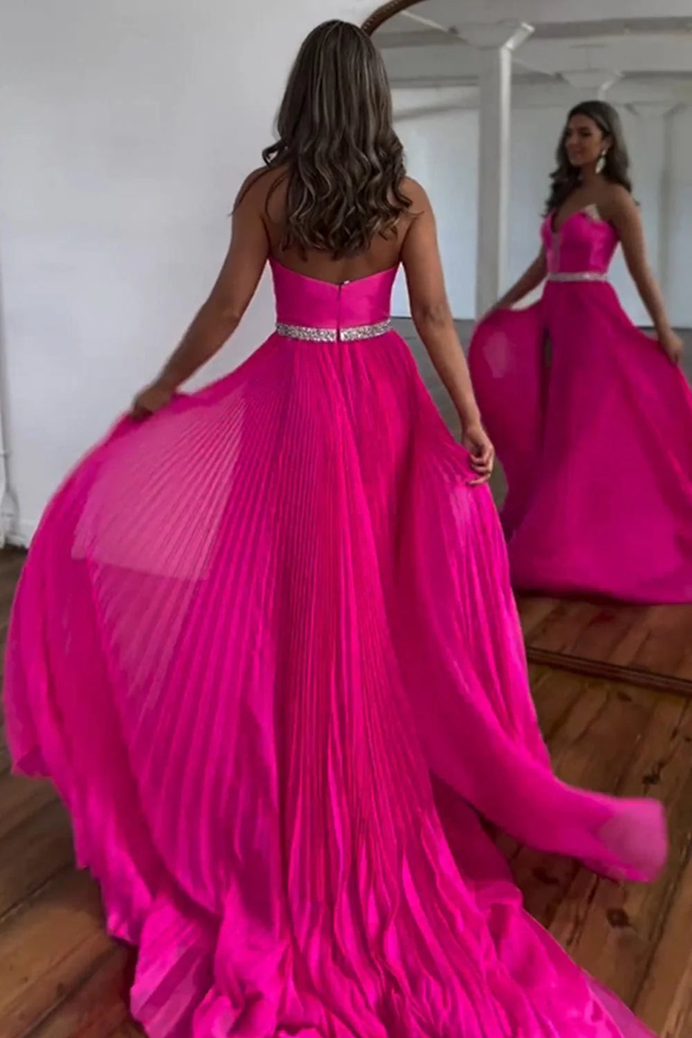 Back view of a hot pink strapless A-line prom dress with a sweep train and zipper closure.