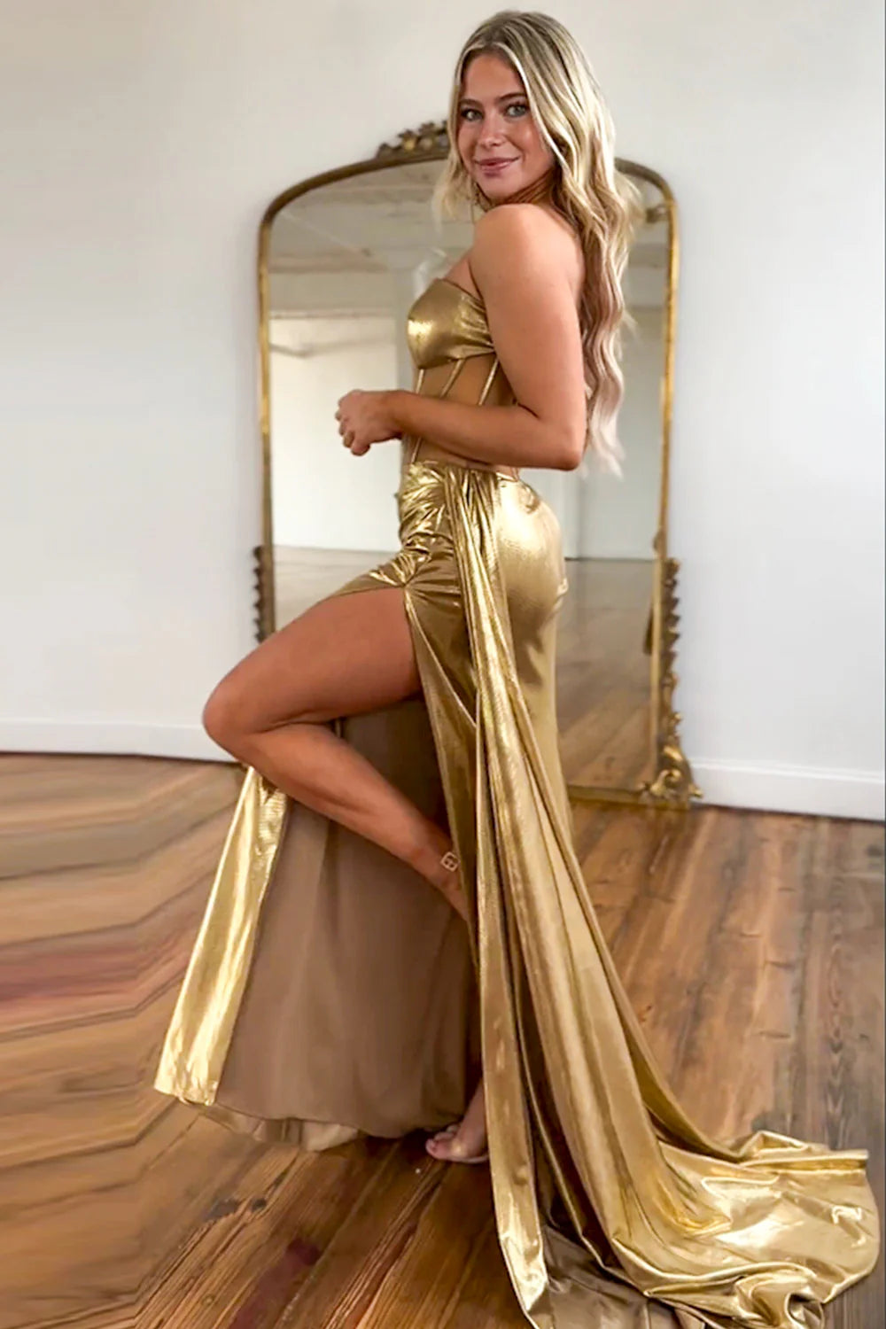 Full-length view of the shimmering metallic gold mermaid gown, highlighting its strapless bodice and flowing train.