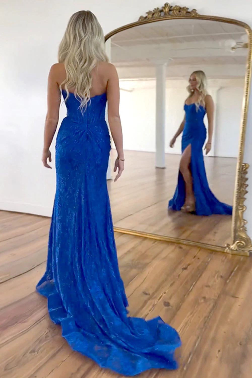 Back view of a woman in a royal blue mermaid prom dress, showing the zipper closure.