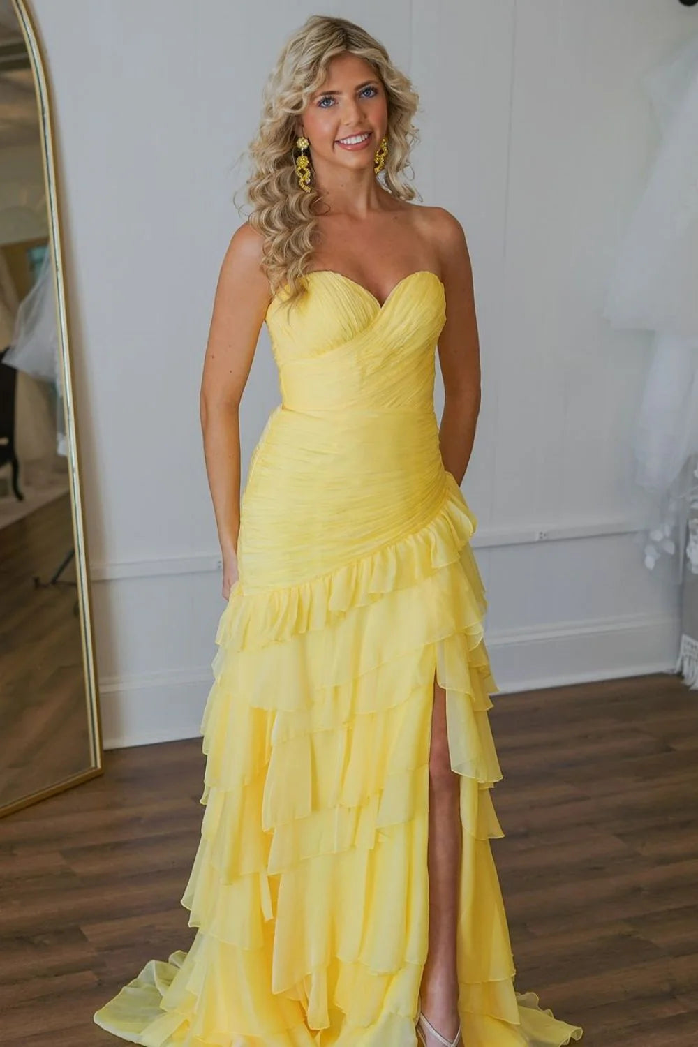 Elegant yellow mermaid prom dress with sweetheart neckline, ruffle tiered skirt, and a high slit, shown from a side angle.