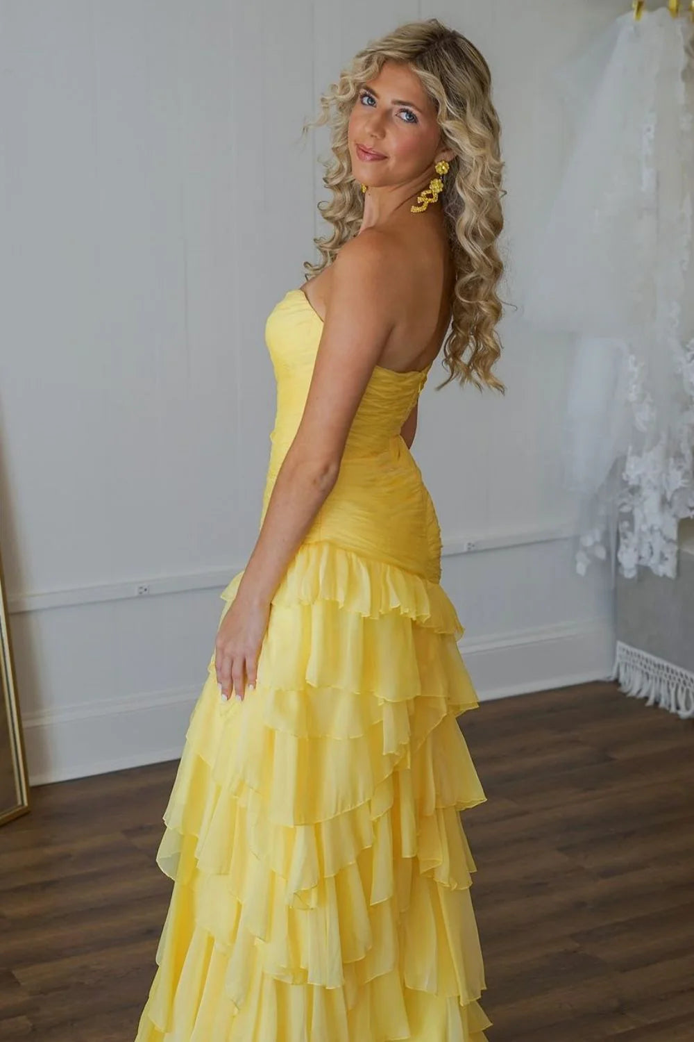 Front view of a stunning yellow mermaid prom dress featuring a sweetheart neckline and voluminous ruffle tiered skirt.