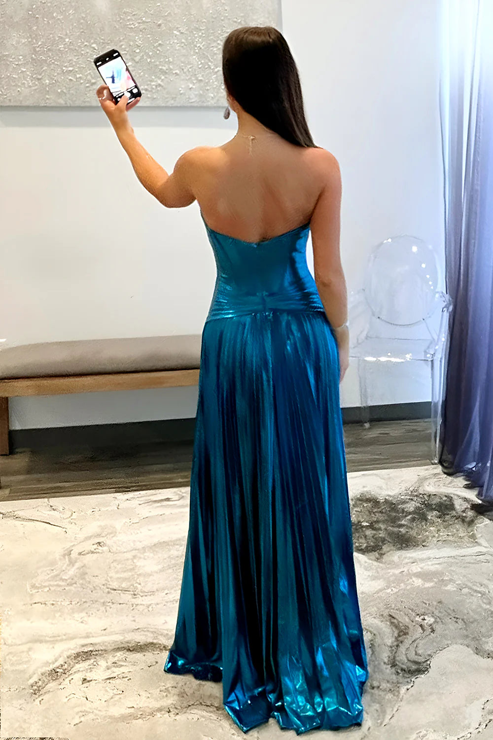 Full view of a woman in a shimmering peacock blue A-line gown with cutout detail.
