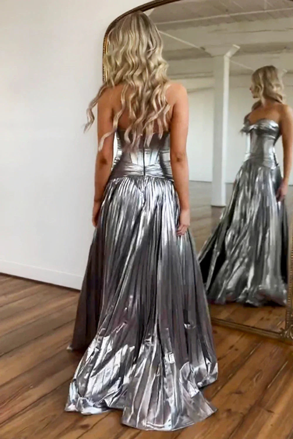 Elegant woman posing in a long peacock blue metallic prom dress with a stylish slit.