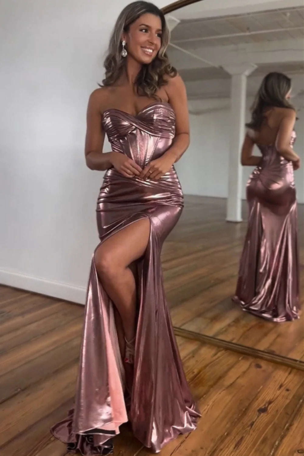 Side profile of a woman in a shimmering metallic magenta mermaid gown with a flowing train.