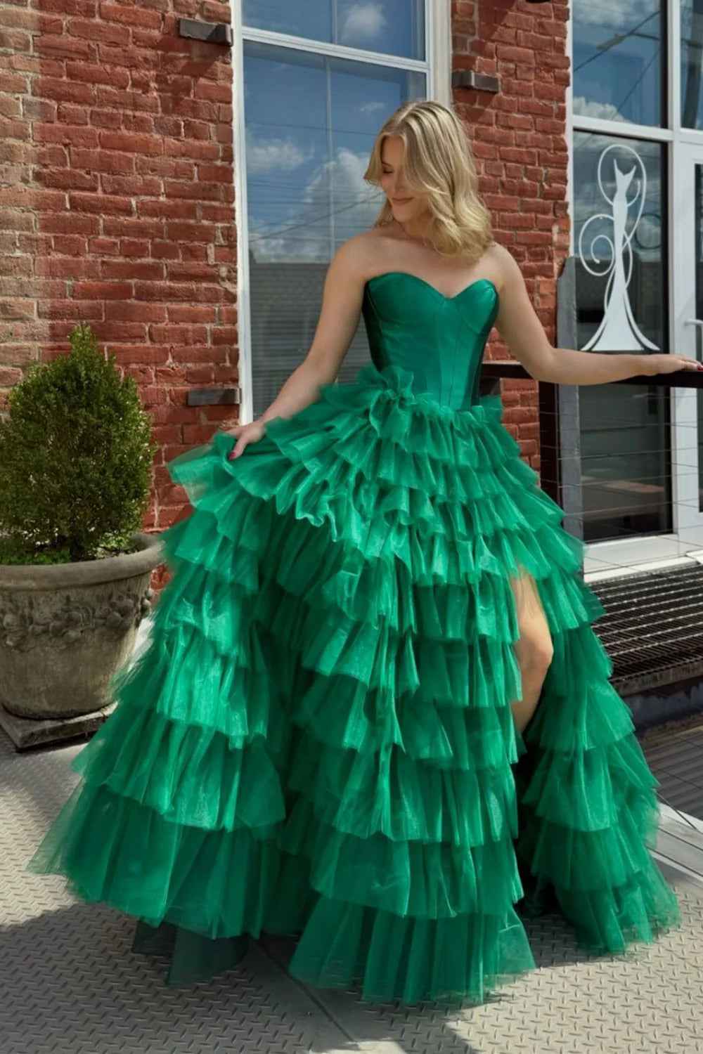 Model wearing a green A-line sweetheart ruffled tiered floor-length prom dress, side view.