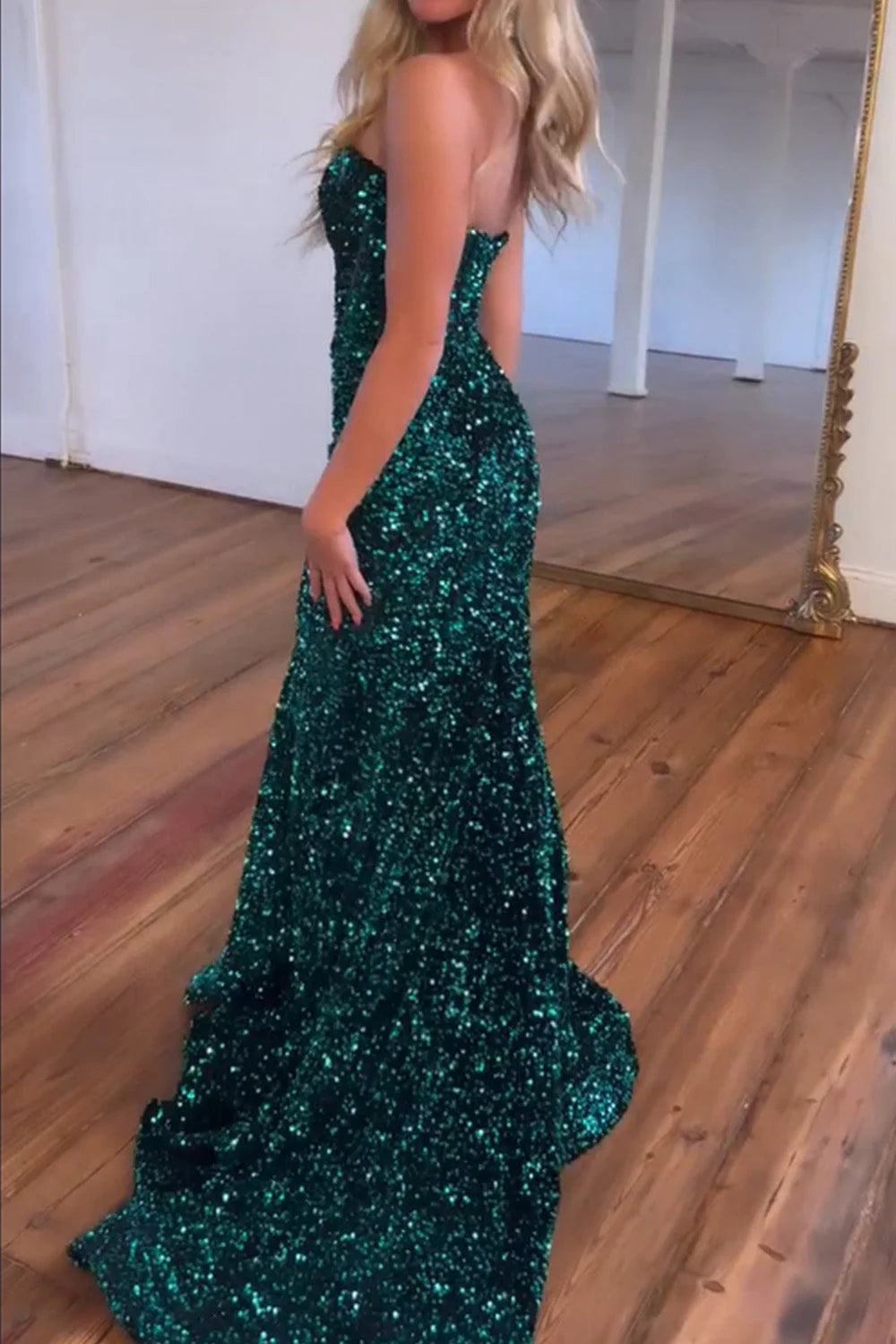 Full view of a woman in a long dark green glitter mermaid gown.
